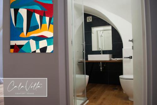 a bathroom with a toilet and a painting on the wall at Cala Volta Comfort House in Torre del Greco