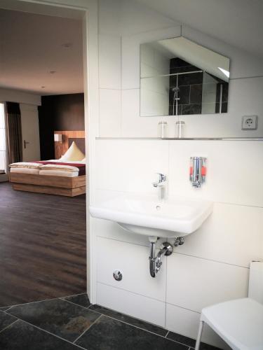 a white bathroom with a sink and a bedroom at Feriendomizil Schlossblick in Blankenburg