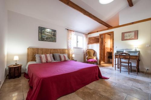 une chambre avec un grand lit avec une couverture rouge dans l'établissement gîte de La Fenière mas Médaille, à Arles