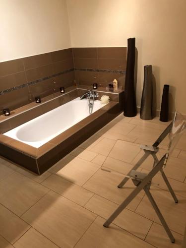 a bath tub in a bathroom with a chair at La maison de Concise - non adapté pour les enfants ni pour les mariages in Thonon-les-Bains