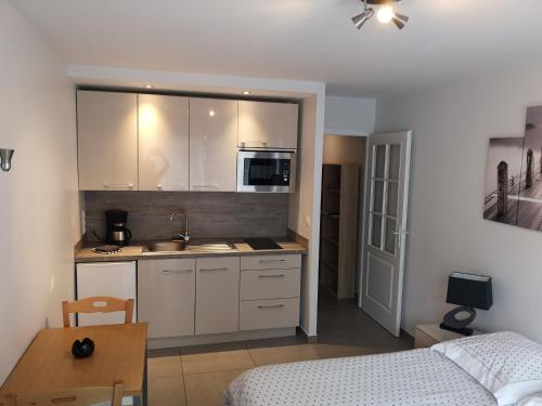 - une cuisine avec des placards blancs et un lit dans une chambre dans l'établissement Le Majestic 103, à Aix-les-Bains