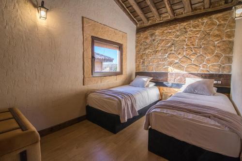 two beds in a room with a stone wall at El BURGO DE OSMA ALOJAMIENTO RURAL VILLA BAGH in El Burgo de Osma
