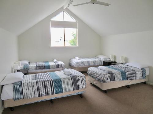een witte kamer met 4 bedden en een raam bij Ocean View Beach House, Margaret River in Gnarabup