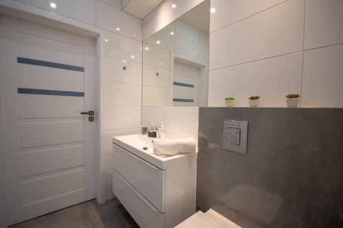 a white bathroom with a sink and a mirror at Apartamenty AP 12 in Częstochowa