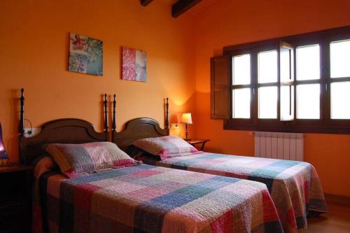 two beds in a room with orange walls and windows at Casa de Aldea La Llosa in Ribadedeva