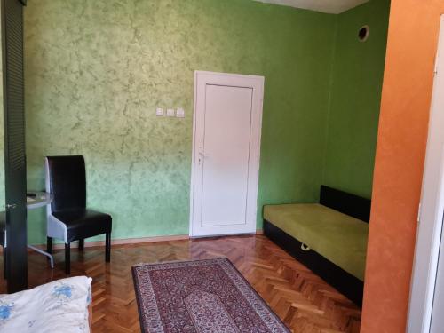 a green room with a bed and a chair at Guest Accommodation Azucki in Novi Bečej