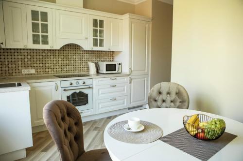a kitchen with a white table and chairs and a table with a bowl of fruit at Old Town River Apartments in Klaipėda