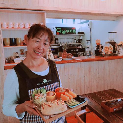 a woman in a kitchen holding a tray of food at Coconutpalm Home in Hengchun