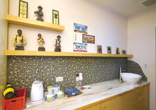 a kitchen with a counter with a sink and shelves at 85 Cape Inn in Kaohsiung