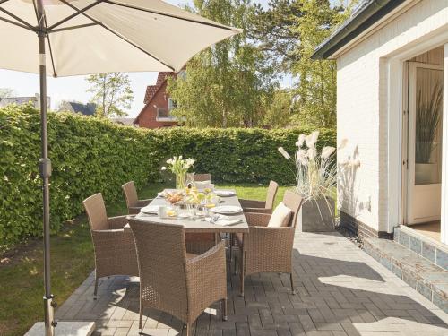 a table and chairs with an umbrella on a patio at Techts Sommerhaus in Timmendorfer Strand