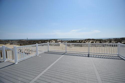 eine große Terrasse mit einem weißen Zaun und dem Strand in der Unterkunft Ocean Club 4011 townhouse in Ocean City