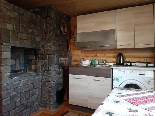 a kitchen with a stove and a stone wall at Дерев'яний будинок з банею in Oriv