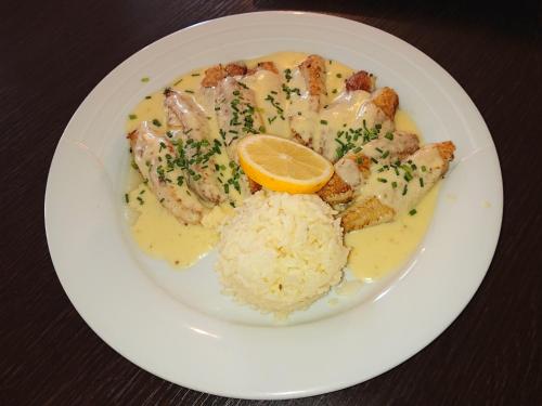 a plate of food with shrimp and rice and an orange slice at Hôtel-Restaurant Le Lion d'Or in Porrentruy