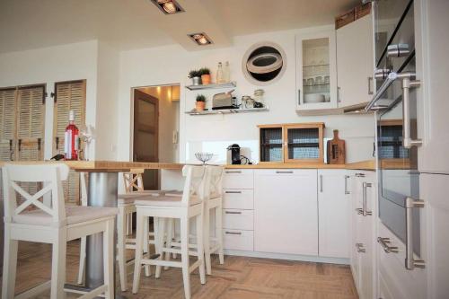 une cuisine avec des placards et des tabourets blancs dans l'établissement emplacement privilégié pour ce bel appartement, à Agay