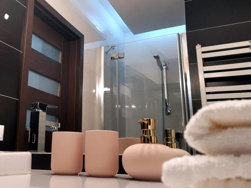 a bathroom with a shower and some white chairs at Emerald Apartament in Białystok