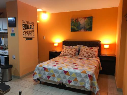 1 dormitorio con 1 cama con paredes de color naranja y 2 lámparas en Virgen del Valle Apart Tucumán - cocheras privadas en San Miguel de Tucumán