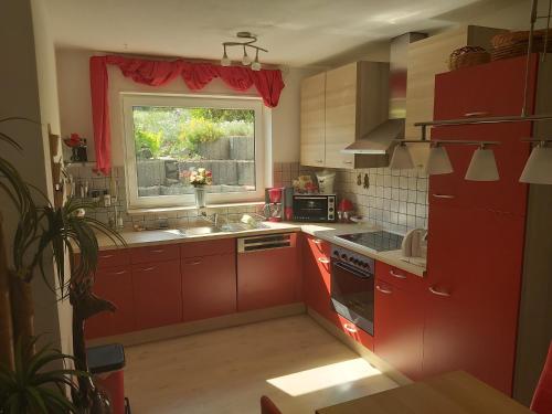 a kitchen with red cabinets and a window and a sink at Ferienwohnung Dinnebier in Leubnitz