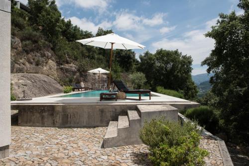 a pool with an umbrella and a bench and a chair and a table at Villa Covela in Baião