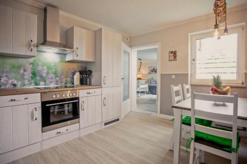 une cuisine avec des placards blancs, un comptoir et une table dans l'établissement Kleine Auszeit, à Bad Segeberg