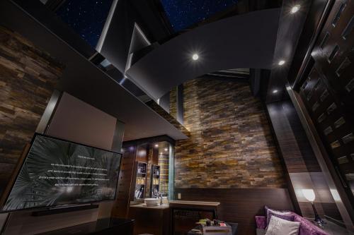 a living room with a tv and a brick wall at HOTEL C.KOHOKU in Shin-yoshidamachi