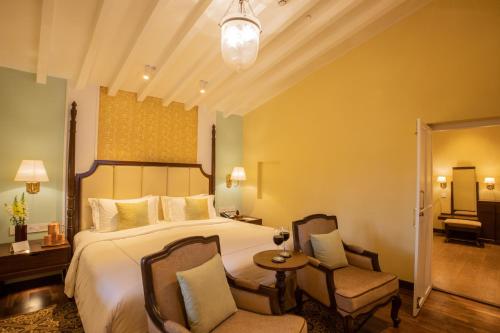 a hotel room with a bed and two chairs at Savoy - IHCL SeleQtions in Ooty