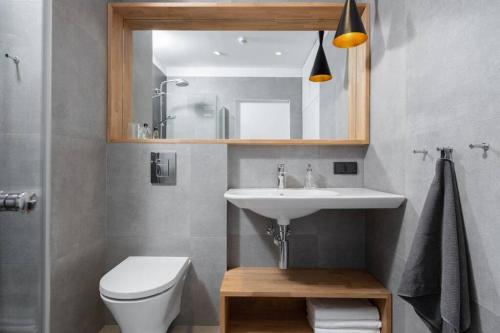 W łazience znajduje się umywalka, toaleta i lustro. w obiekcie Stylish Apartment Luminis in Krakow's Kazimierz w Krakowie