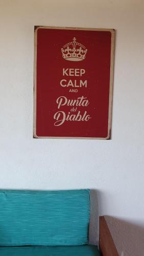 a sign on a wall above a blue couch at Ammunaini in Punta Del Diablo