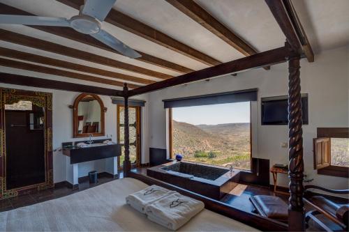 a bedroom with a tub and a view of a mountain at La Almendra y El Gitano in Agua Amarga