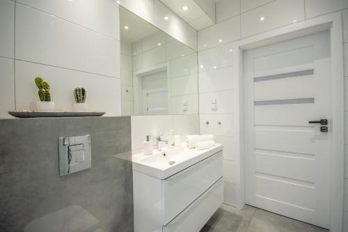 a white bathroom with a sink and a door at Apartamenty AP 11 in Częstochowa