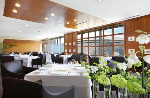a restaurant with white tables and black chairs and flowers at Tokyo Dome Hotel in Tokyo