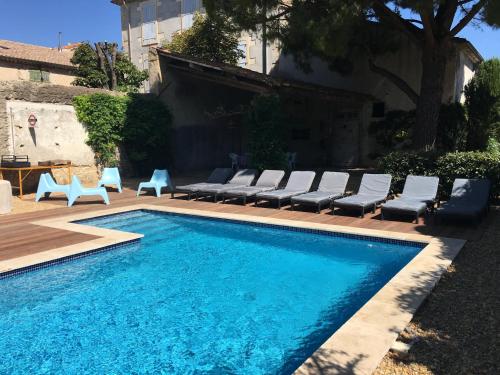 une piscine avec des chaises longues à côté d'un bâtiment dans l'établissement Le Rouzet, à Cazouls-lès-Béziers