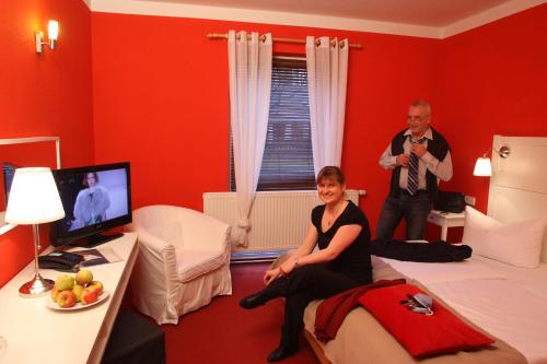 un hombre y una mujer en una habitación con paredes rojas en Schlossparkhotel Sallgast, en Sallgast