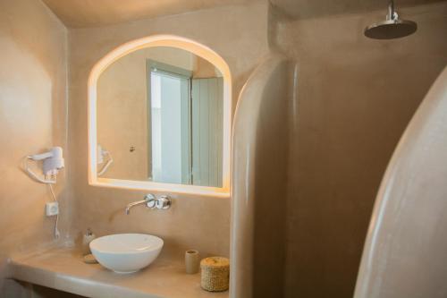 a bathroom with a sink and a mirror at Amphitrite Suites Santorini in Vóthon