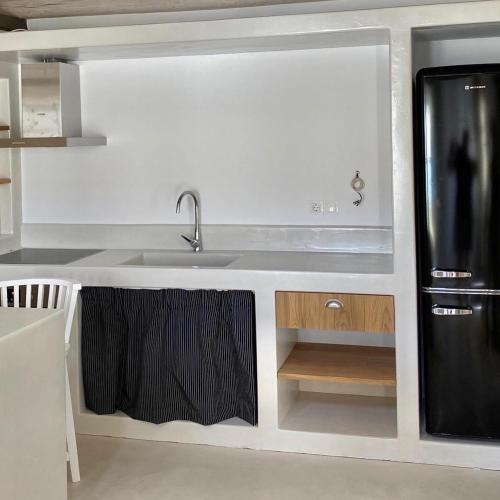 a kitchen with a sink and a black refrigerator at LAINI LUXURY SUITES in Pómbia