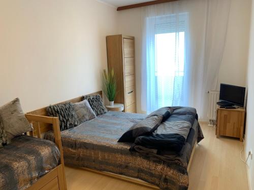 ein Schlafzimmer mit einem Bett, einem Sofa und einem TV in der Unterkunft Lakeside Wellness Apartman in Siófok