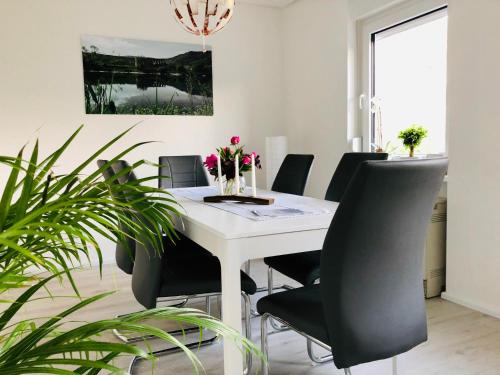 a dining room with a white table and black chairs at Ferienhaus Calmont in Bremm