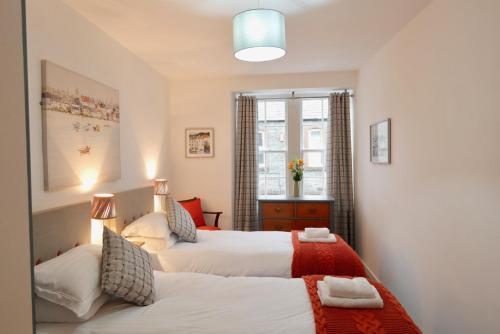 a bedroom with two beds and a window at Providence Cottage in Kirkcudbright