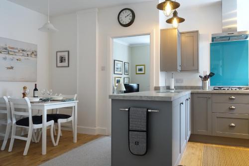 a kitchen with a table and a clock on the wall at Providence Cottage in Kirkcudbright