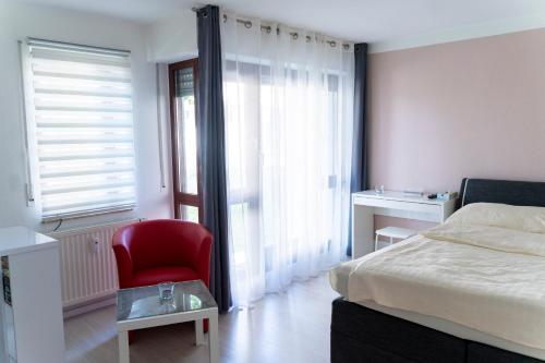 ein Schlafzimmer mit einem Bett und einem roten Stuhl in der Unterkunft Ferienwohnung Dennis in Lörrach