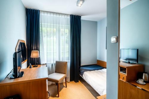 a hotel room with a desk and a bed and a television at Hotel Nawigator Szczawnica in Szczawnica