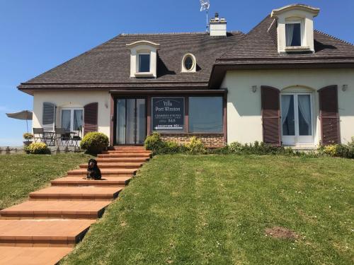 a dog sitting in front of a house at La Villa Port Winston - Face Mer B&B in Saint-Côme-de-Fresné