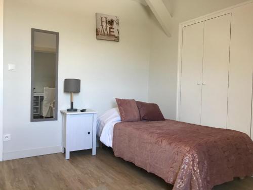 a bedroom with a bed and a lamp and a mirror at La Villa Port Winston - Face Mer B&B in Saint-Côme-de-Fresné
