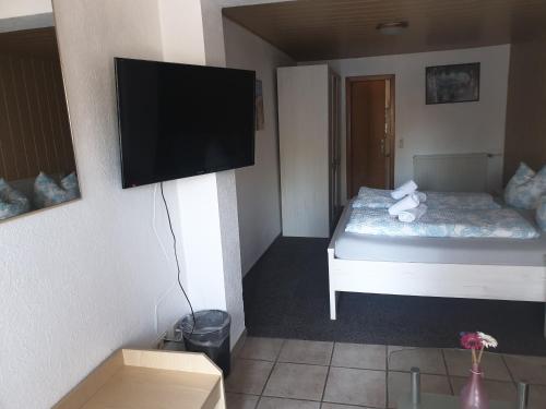 a small room with a bed and a flat screen tv at Hotel Nordseegruß in Norddeich