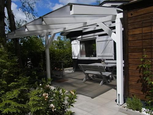 a white pergola with a table on a patio at Waldhütte am See in Klingberg