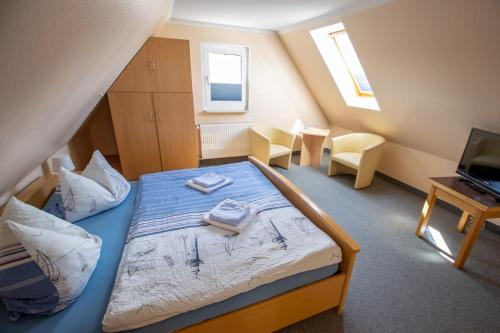 a bedroom with a bed with two towels on it at Hotel Pension Nordseewelle in Norddeich