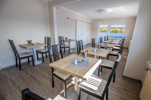 a dining room with wooden tables and chairs at Hotel Pension Nordseewelle in Norddeich