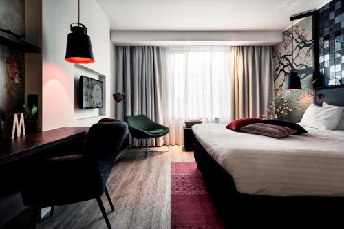 ein Hotelzimmer mit einem Bett, einem Schreibtisch und einem Stuhl in der Unterkunft M Hotel in Genk