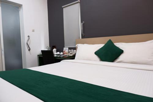 - une chambre avec un grand lit blanc et un oreiller vert dans l'établissement Ara Inn Bed And Breakfast by ecommerceloka, à Kuta