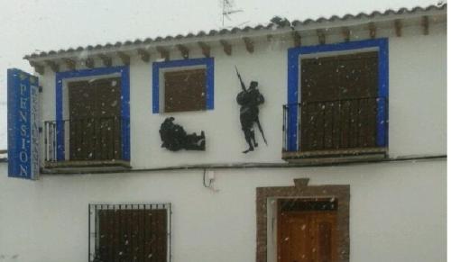 a building with two windows and a man hanging out of them at Hostal Restaurante Ego's in Campo de Criptana