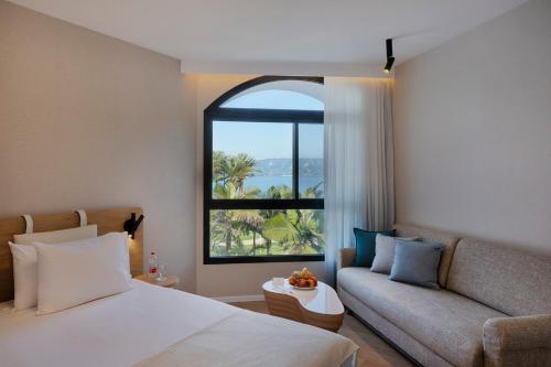 a bedroom with a bed and a couch and a window at Gai Beach Hotel in Tiberias